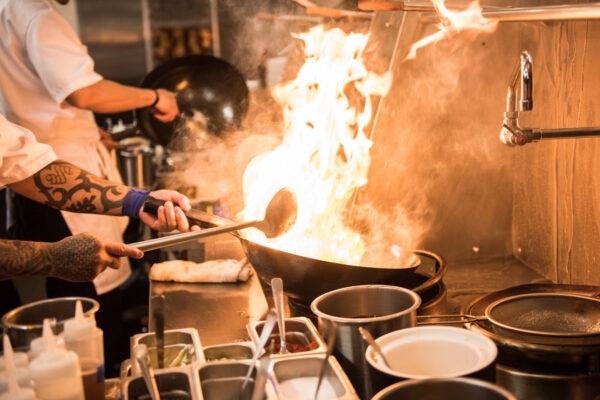 Chefs cooking at a wok, with flames leaping out